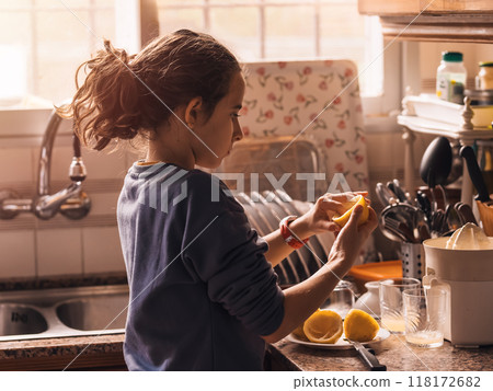 Girl Squeezing Fresh Lemons in Kitchen 118172682