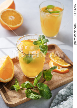 Freshly squeezed juice in a glass with fresh oranges, mint and ice on a light background  118173207