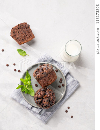 Chocolate muffins on a plate with mint on a light background with milk and morning shadow. 118173208