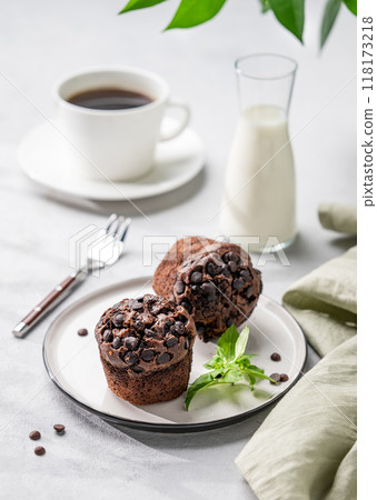 Chocolate muffins on a white plate with mint on a light background with cup of coffee, milk Chocolate muffins on a white plate with mint on a light background with cup of coffee, milk 118173218