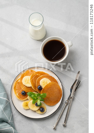 Delicious banana pancakes with fresh fruit slices, berries, mint and honey on a light background 118173246
