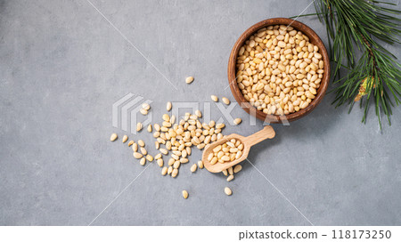 Pine nuts in a bowl and a scattered on a blue background with branches of pine needles. Pine nuts in a bowl and a scattered on a blue background with branches of pine needles. 118173250