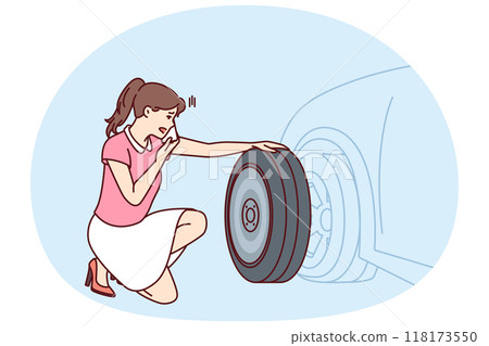 Woman looks at punctured car tire trying to call for help to change tire or haul automobile 118173550