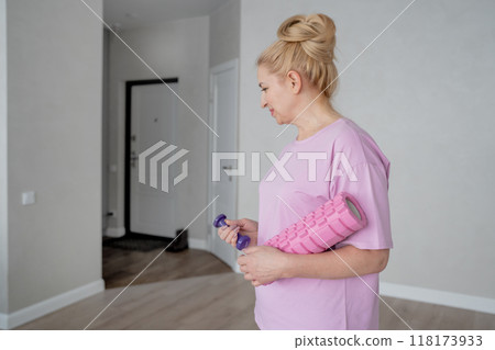 A woman is engaging in an online home exercise and stretching routine on a pink mat. Online fitness. A woman is engaging in an online home exercise and stretching routine on a pink mat. Online fitness. 118173933