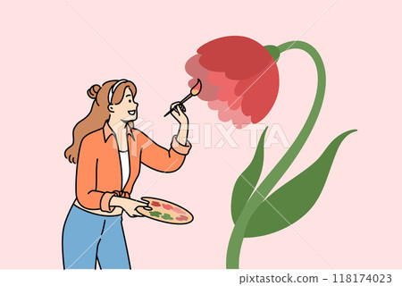 Woman artist paints flower on wall to decorate interior, uses wooden palette and brush 118174023