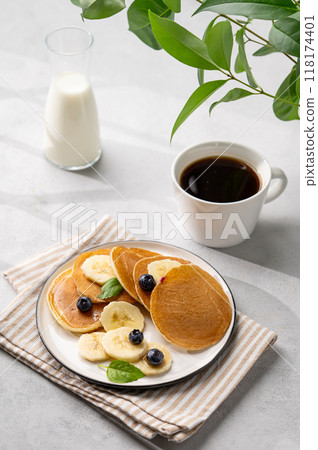 Delicious banana pancakes with fresh fruit slices, berries, mint and honey on a light background 118174401