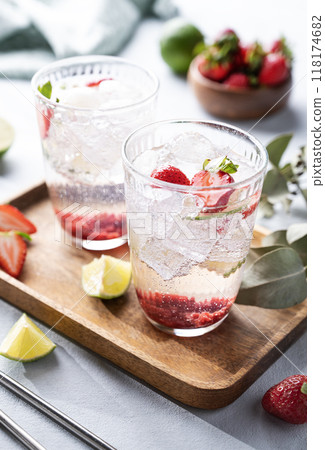 Fresh strawberry mojito in a glass with berries, lime, mint and ice in a wooden plate  118174682
