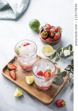 Fresh strawberry mojito in a glass with berries, lime, mint and ice in a wooden plate Fresh strawberry mojito in a glass with berries, lime, mint and ice in a wooden plate 118174694