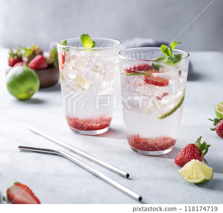 Fresh strawberry mojito in a glass with berries, lime, mint and ice on a light background 118174719
