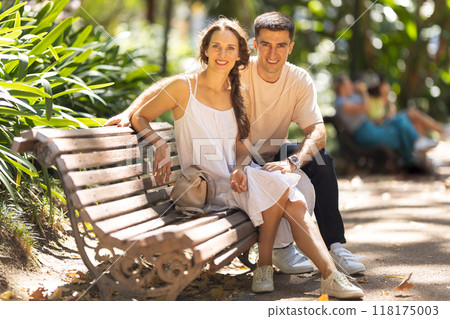 Young couple relaxing on bench in park Young couple relaxing on bench in park 118175003