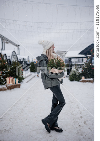 Portrait of young blond woman walking in the city with a bouquet of fresh fir branches 118175069