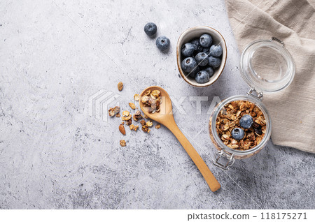 Homemade baked granola with nuts and fresh blueberry in a jar on a light background. Homemade baked granola with nuts and fresh blueberry in a jar on a light background. 118175271