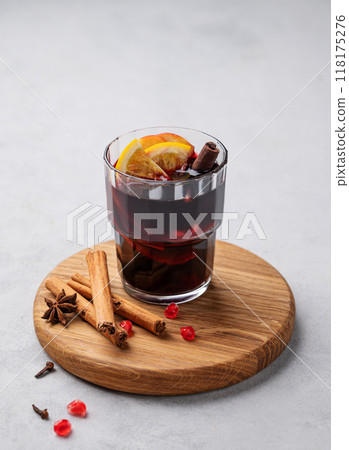 Mulled wine with orange, apple and cinnamon in glass on a wooden board on a light background Mulled wine with orange, apple and cinnamon in glass on a wooden board on a light background 118175276