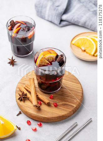 Mulled wine with orange, apple and cinnamon in glass on a wooden board on a light background  118175278