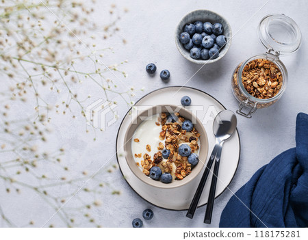 The concept of a healthy breakfast of yogurt, granola and fresh blueberry on a blue background The concept of a healthy breakfast of yogurt, granola and fresh blueberry on a blue background 118175281