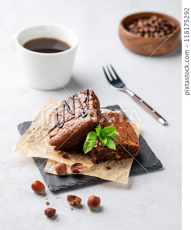 Pieces of chocolate brownies with hazelnuts and salted caramel on baking paper on a light background 118175292