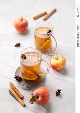Homemade apple cider with apples and cinnamon in cups on a light background with fresh fruits 118175300