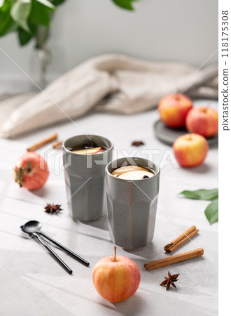 Homemade apple punch with apples and cinnamon in gray cups on a light background with fresh fruits 118175308