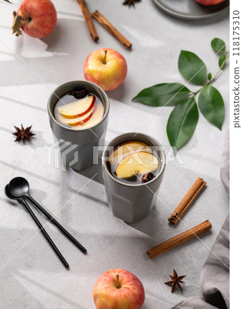 Homemade apple punch with apples and cinnamon in gray cups on a light background with fresh fruits  118175310