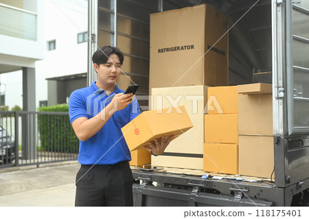Male courier holding cardboard box and using smartphone to confirm or manage deliveries Male courier holding cardboard box and using smartphone to confirm or manage deliveries 118175401