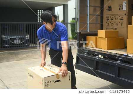Delivery man in uniform unloading cardboard boxes from from van. Moving service and transportation concept 118175415