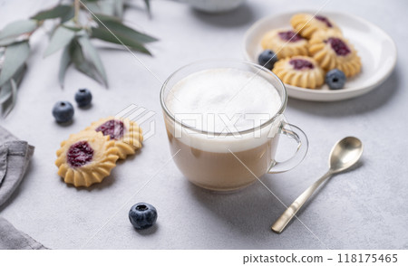 Cappuccino or latte with milk foam in a cup with  homemade berry cookies and blueberries  118175465
