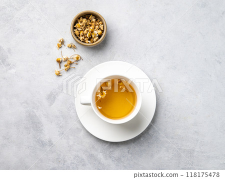 Chamomile herbal tea in a white cup on a light background with dry flowers. Chamomile herbal tea in a white cup on a light background with dry flowers. 118175478