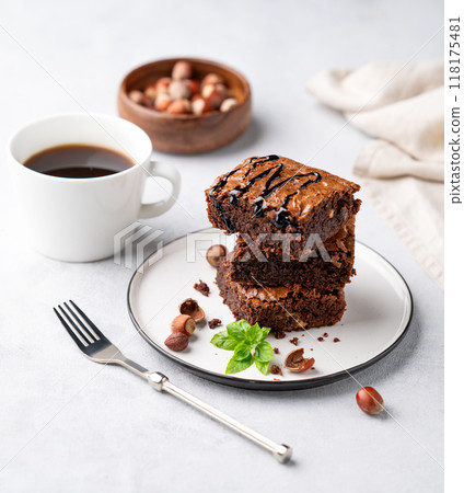 A stack of chocolate brownies with mint, hazelnuts and salted caramel on a plate  118175481