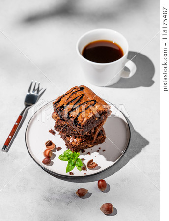 A stack of chocolate brownies with mint, hazelnuts and salted caramel on a white plate A stack of chocolate brownies with mint, hazelnuts and salted caramel on a white plate 118175487