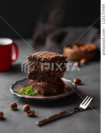 Cocoa pours on to a stack of chocolate brownies with hazelnuts and salted caramel  118175499