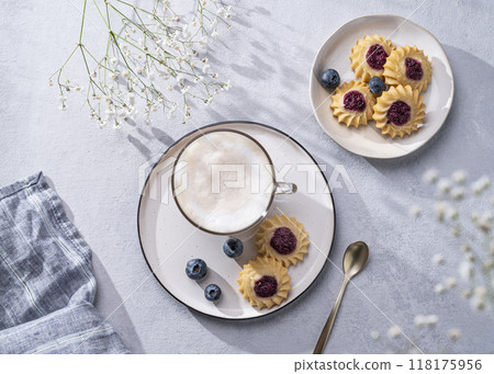 Cappuccino or latte with milk foam in a cup with handmade berry cookies and blueberries Cappuccino or latte with milk foam in a cup with handmade berry cookies and blueberries 118175956