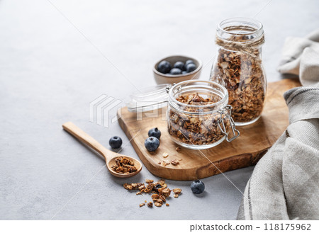 Homemade baked granola with nuts and fresh blueberry in a jar on a light background. Homemade baked granola with nuts and fresh blueberry in a jar on a light background. 118175962