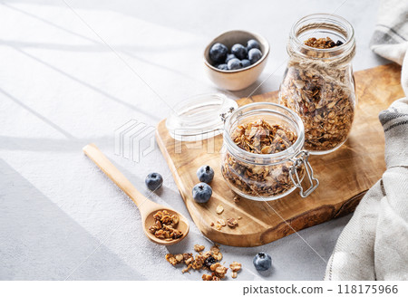 Homemade baked granola with nuts and fresh blueberry in a jar on a light background 118175966
