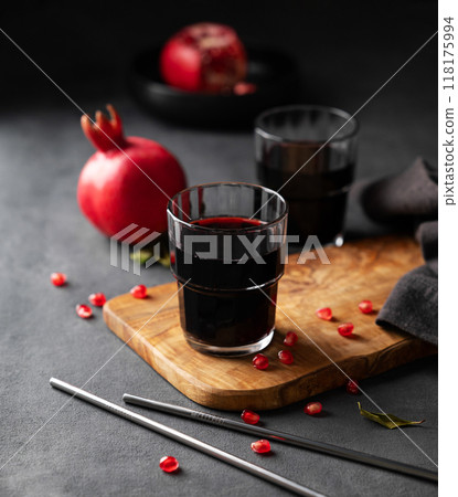 Natural pomegranate juice in a glasses on a wooden board on a dark background with fresh fruit Natural pomegranate juice in a glasses on a wooden board on a dark background with fresh fruit 118175994