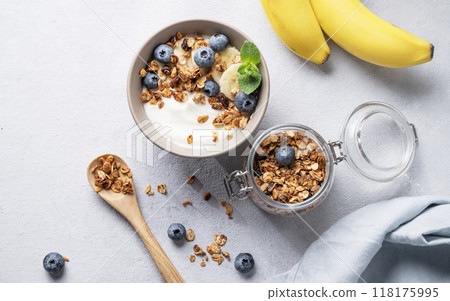 Homemade baked granola with yogurt, blueberries and banana in a bowl on a light background Homemade baked granola with yogurt, blueberries and banana in a bowl on a light background 118175995