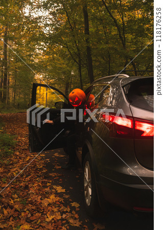 Autumn SUV with Driver with Pumpkin Head in Forest Autumn SUV with Driver with Pumpkin Head in Forest 118176258