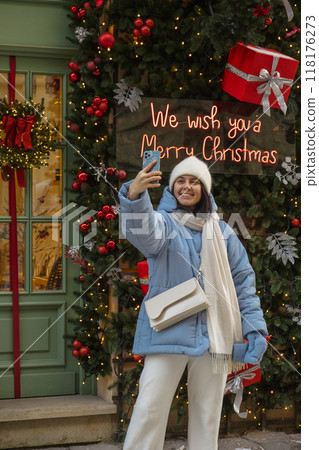 woman walking by city street decorated for christmas woman walking by city street decorated for christmas 118176273