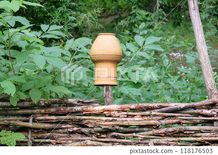 Retro design. Clay jug on a wicker fence in countryside. Terracotta pot. Retro design. Clay jug on a wicker fence in countryside. Terracotta pot. 118176503
