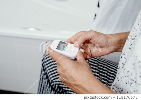 man measuring his glucose level in the bathroom 118176575