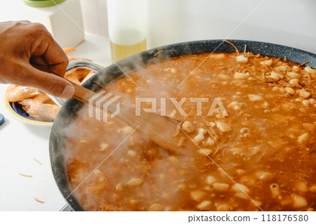 man cooking a spanish fideua in a paella pan 118176580