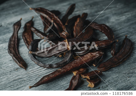 bunch of ripe carob pods on a wooden table 118176586