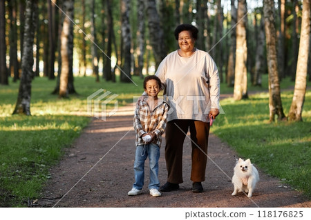 Portrait of African American granny and her grandson walking with snow white spits in green park Portrait of African American granny and her grandson walking with snow white spits in green park 118176825