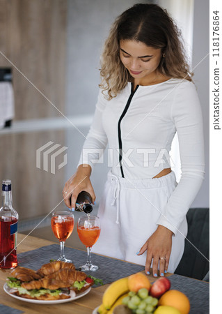 Attractive curly hair girl preparing cocktail at home. Food and drinks on wooden table 118176864
