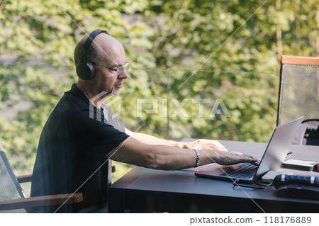 Professional video editor editing video at vacation. Middle aged man using laptop and hard drives Professional video editor editing video at vacation. Middle aged man using laptop and hard drives 118176889