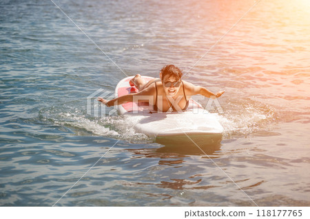 Woman sup sea travel. Sports girl on a surfboard in the sea on a sunny summer day. In a black bathing suit, he sits on a sapa in the sea. Rest on the sea. Woman sup sea travel. Sports girl on a surfboard in the sea on a sunny summer day. In a black bathing suit, he sits on a sapa in the sea. Rest on the sea. 118177765
