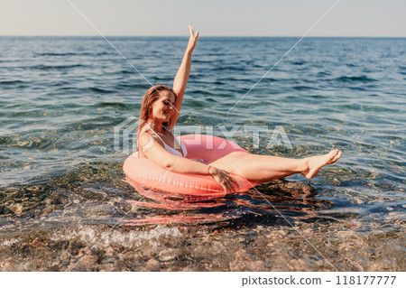 A woman is floating on a pink inflatable raft in the ocean 118177777