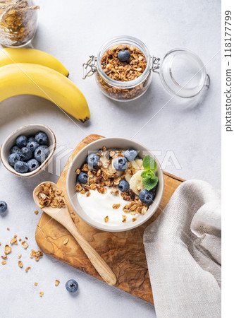 Homemade baked granola with yogurt, blueberries and banana in a bowl on a light background  118177799