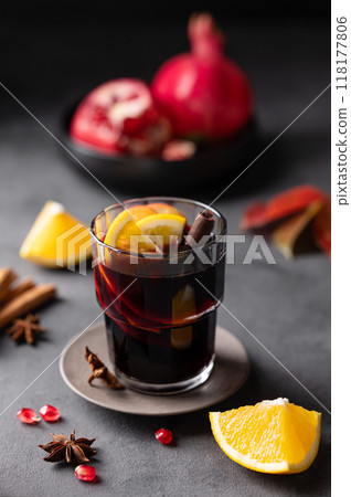Mulled wine with orange, apple, pomegranate and cinnamon in glass on a dark background. Mulled wine with orange, apple, pomegranate and cinnamon in glass on a dark background. 118177806