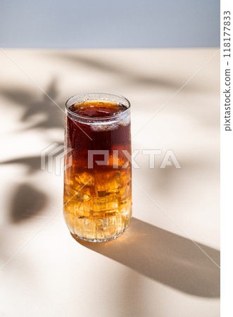 Long Island iced tea cocktail with hard liquor with rum, cola, lemon and ice on yellow background  118177833