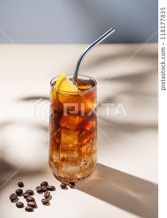 Coffee with tonic in a tall glass with ice and lemon on a yellow background with coffee beans Coffee with tonic in a tall glass with ice and lemon on a yellow background with coffee beans 118177835